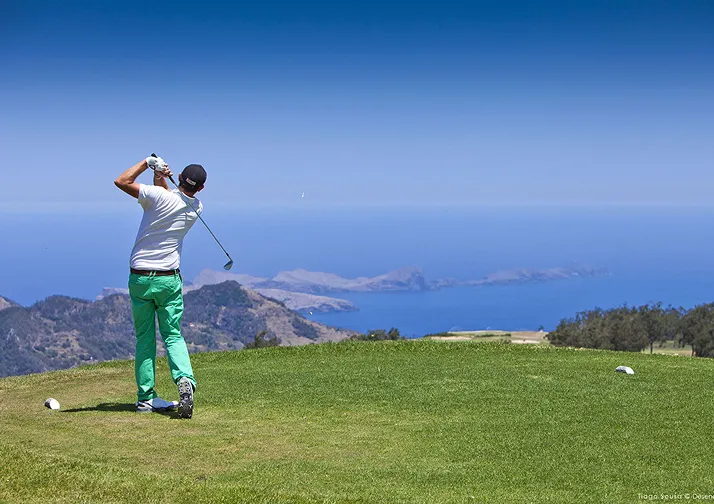 Golfer swinging with ocean backdrop
