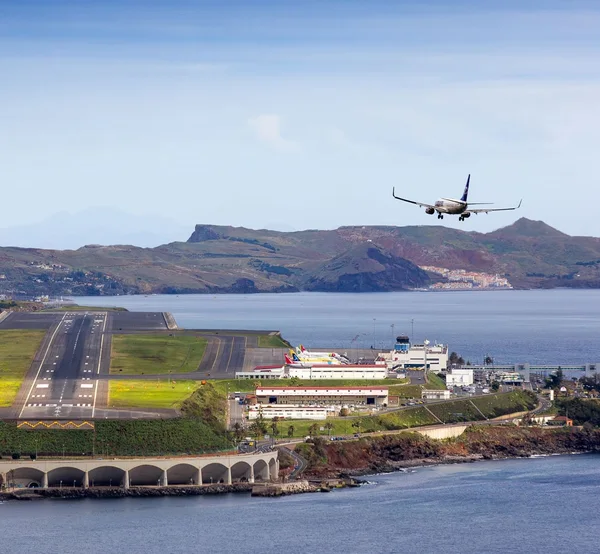 Aerial view of Madeira Airport's runway built on pillars over the sea, plane on approach