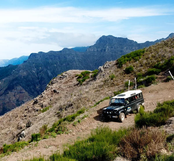 An off-road 4x4 vehicle parked on a mountain ridge trail