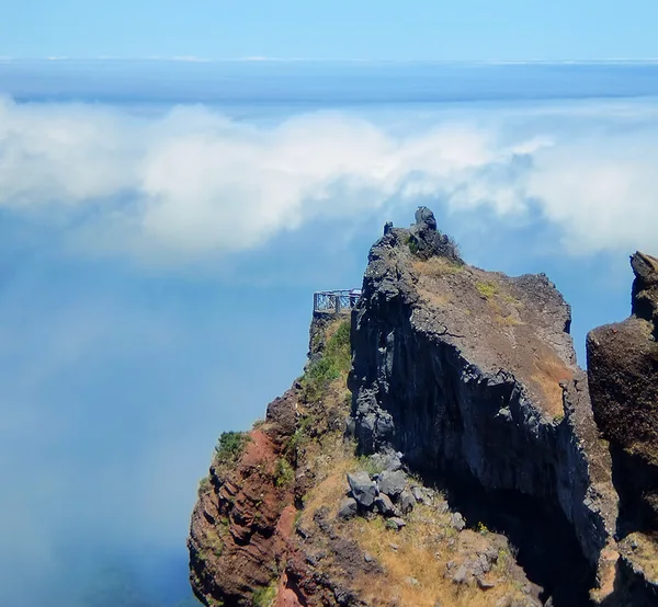 A rocky mountain viewpoint rising above a sea of clouds