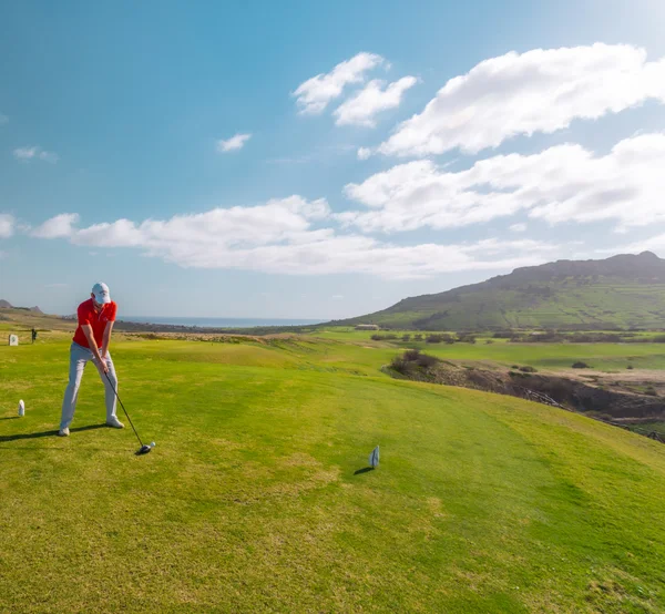 A golfer driving on a Porto Santo golf course fairway overlooking the sea