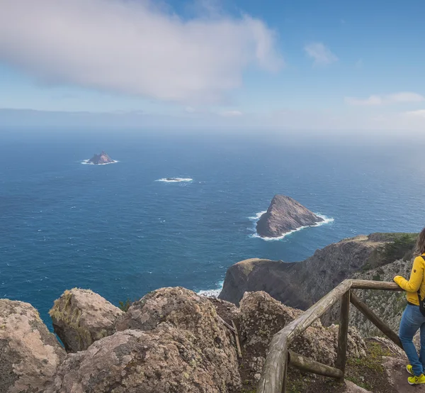 A hiker looking out over sea stacks from the Pico Branco trail